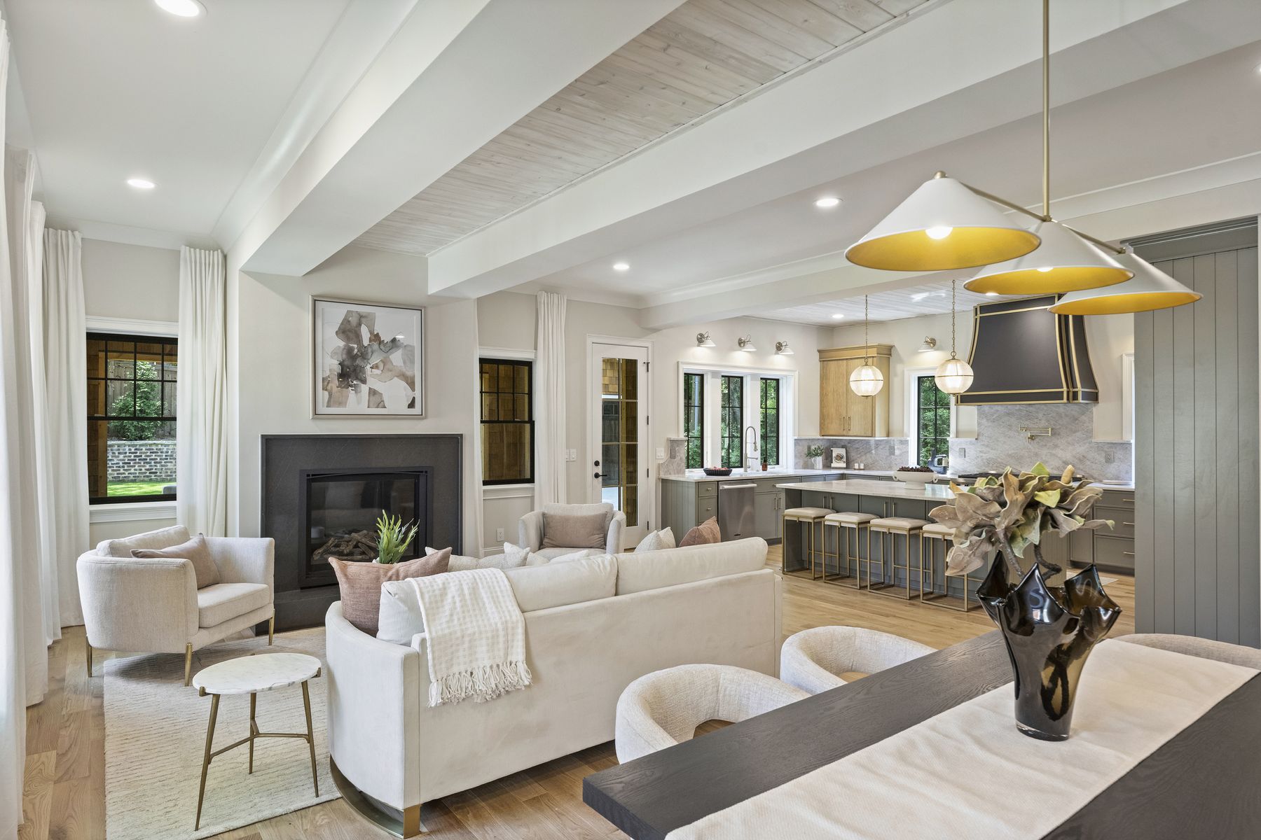 Great room with a beamed ceiling and a black stone fireplace, open to the kitchen